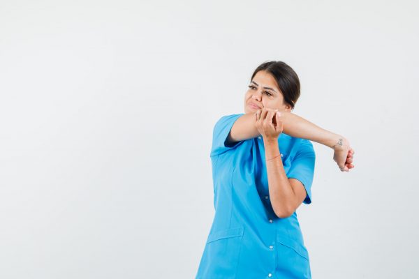 Female doctor stretching arm while looking away in blue uniform front view.